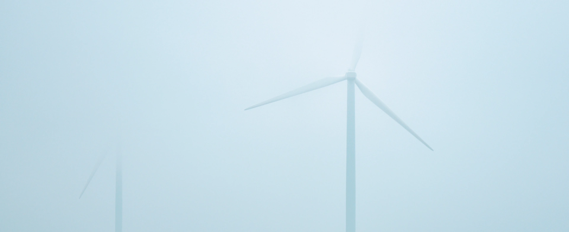 Zwei Windräder bei Nebel, was ist eine Energiegemeinschaft und welche Vorteile bietet sie